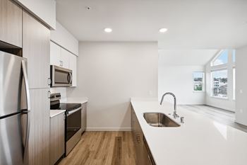 A modern kitchen with a stainless steel refrigerator and a wooden floor.